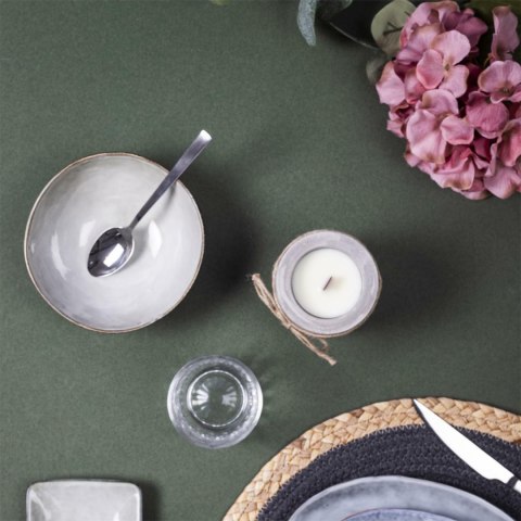 Oliwkowa ceramiczna misa japandi Midori I z łyżką, szklanką i świecą na ciemnozielonym obrusie, widok z góry.