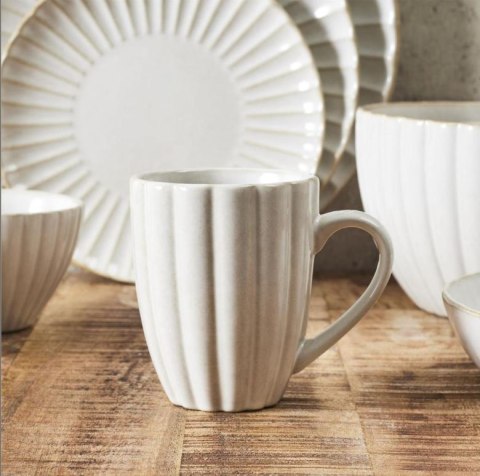 Beżowy ceramiczny kubek z uchem japandi Beju Magu II z pionowym tłoczeniem stojący na drewnianym stole.